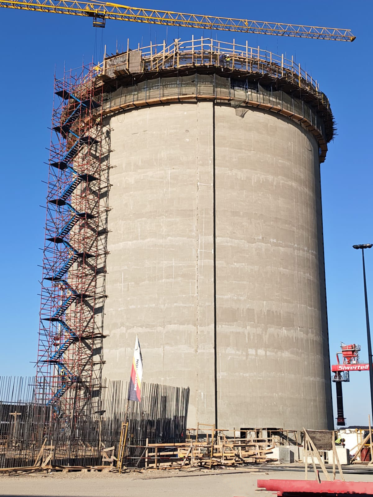 A completed full-height cement silo at the Bulk Cement Export Station, with the Siwertell shiploader standing on the quay beside it