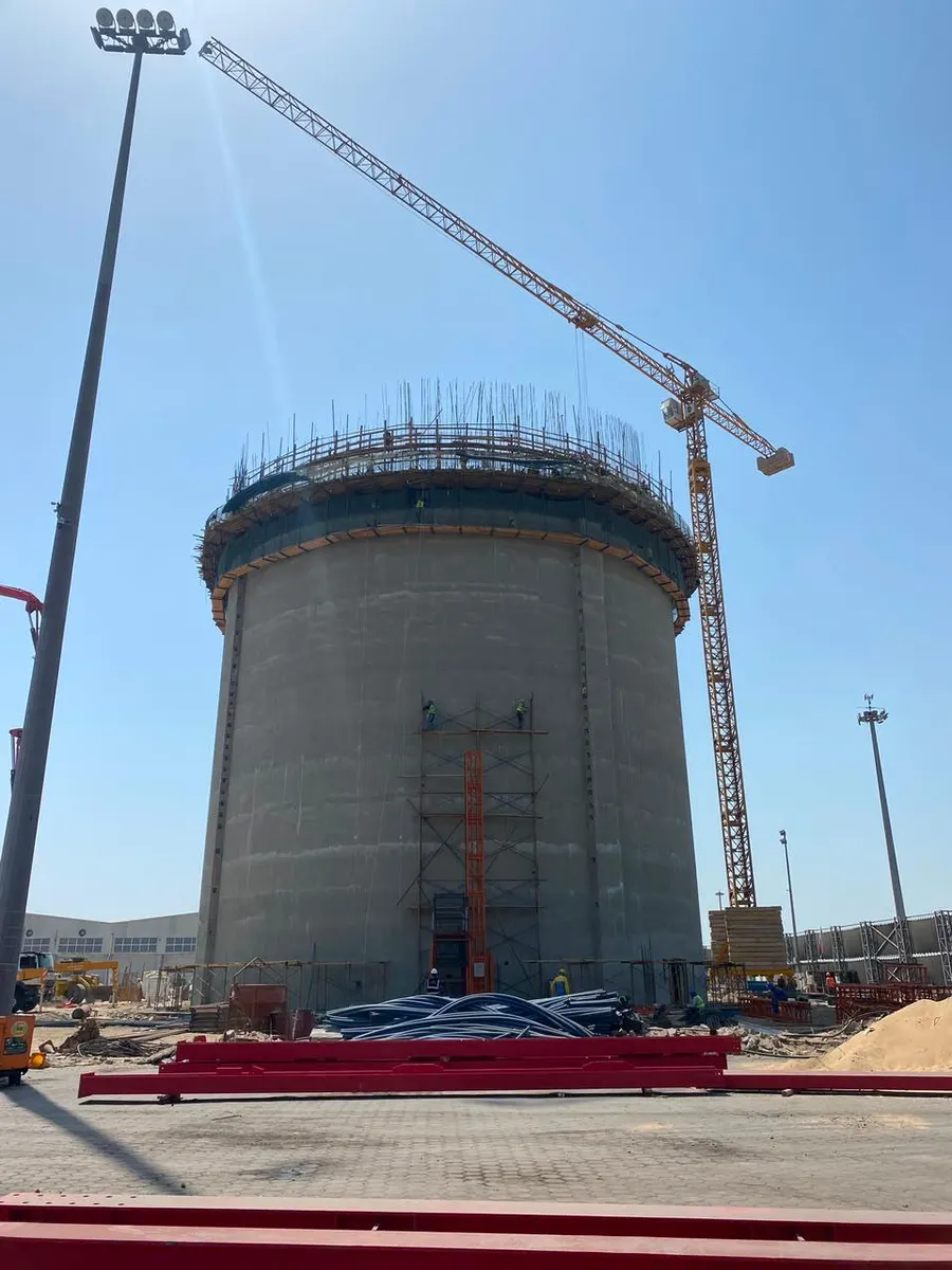 Completed silo wall with roof starter bars projecting from the top ring, served by a tower crane