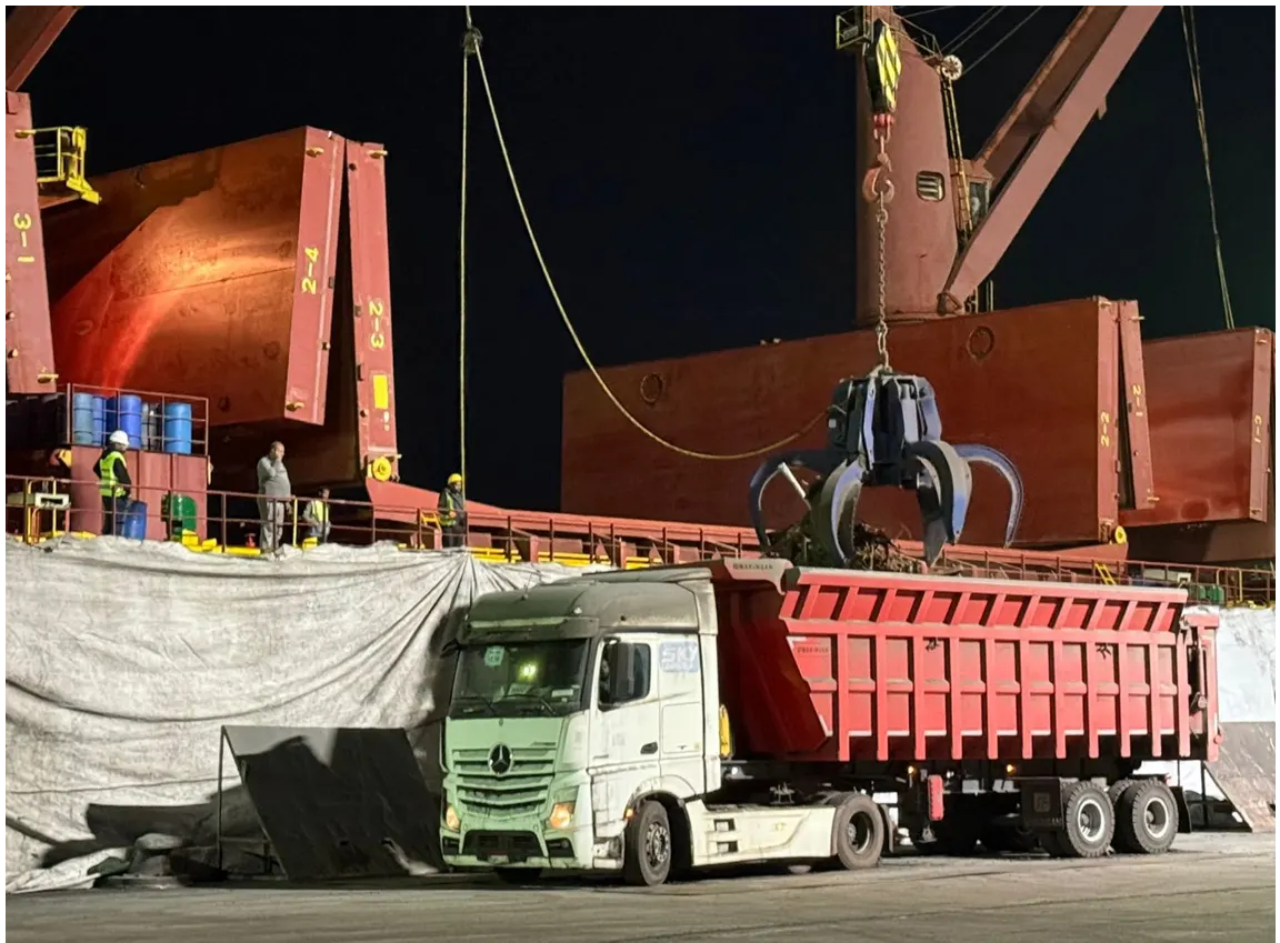 Grab crane discharging scrap directly into a high-sided truck at the quay
